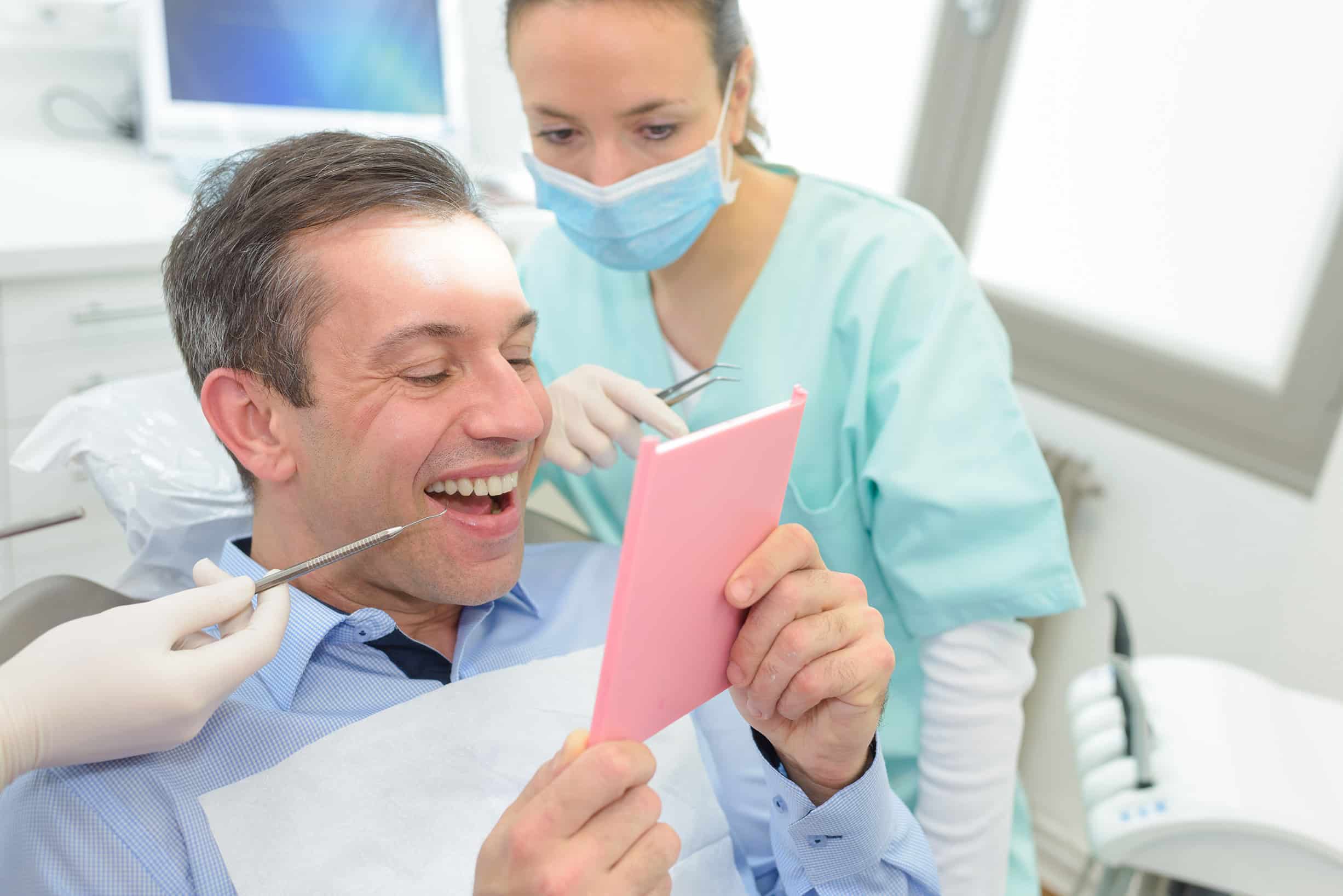 man looking at teeth at dental appt in Clark, NK